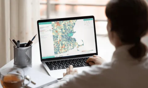 image looking over a woman's shoulder at a laptop with a map on the screen,