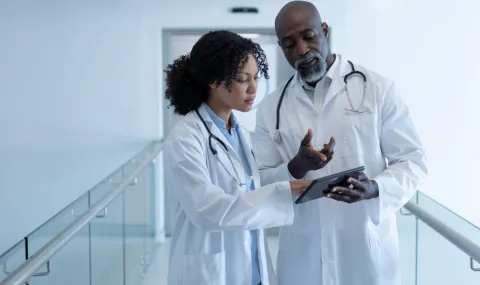 image of two doctors reviewing information on a tablet in a hospital hallway