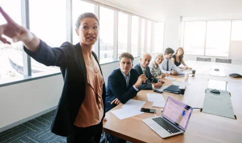 Image of a woman giving a presentation in a conference room.