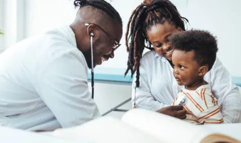 image of a doctor with a young boy and his mother in an exam room